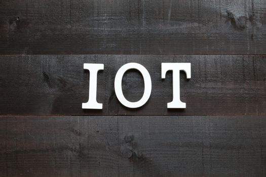 White letters representing the acronym of the Internet of things concept on wooden background