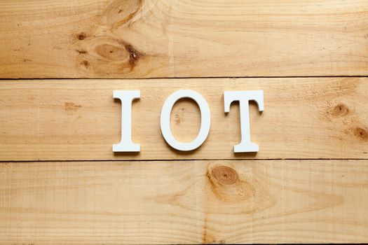 White letters representing the acronym of the Internet of things concept on wooden background