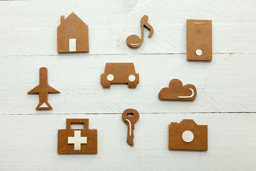 Set of web icons or graphical illustrations cut from cardboard and placed on white wooden background