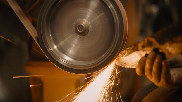 Craftsman uses a belt sander in a mechanical workshop.