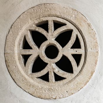 Round stone window within an ogival symmetrical design.
