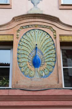 Colorful peacock sculpture adorns a historic building in Italy.