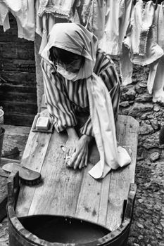Riva del Garda, Italy - December 26, 2015: Laundress washes clothes with soap and water on a wooden board.