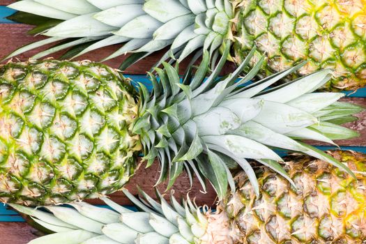 Three large pineapple fruits placed closely next to each other in alternating arrangement as background