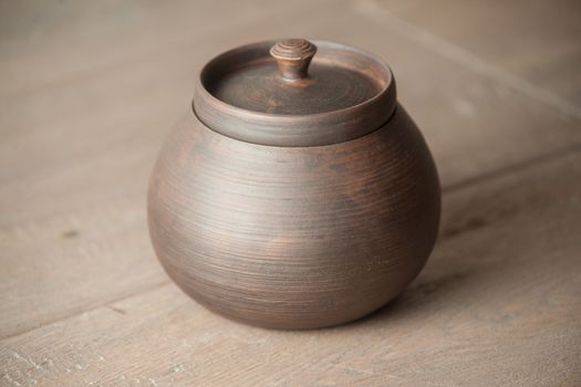 Traditional handcrafted brown pot with a cap