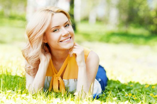Smilng happy young woman lying on green grass meadow