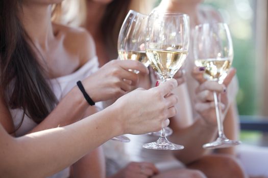 Happy female friends toasting white wine outdoors