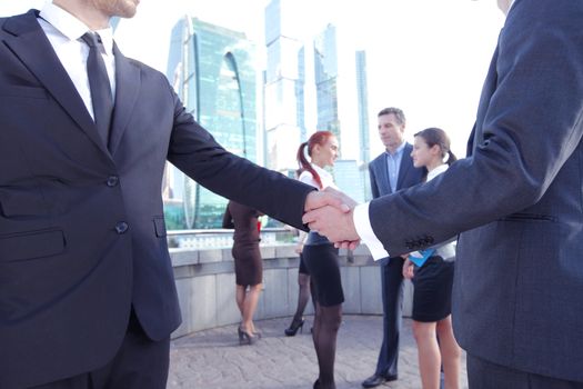 Business handshake, the deal Is finalized by group of people outside