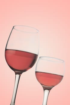 Vertical front view of two rose wine glasses isolated on pink background