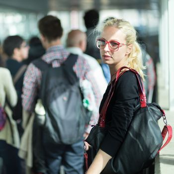 Young blond caucsian woman waiting in queue to board a plane.