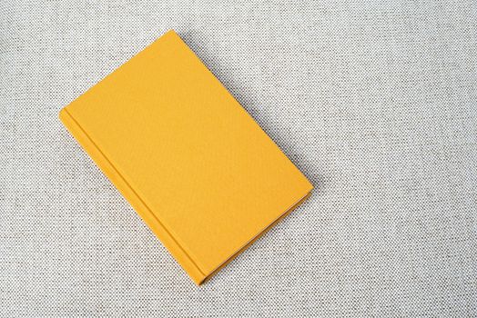 Yellow book on the grey fabric material background