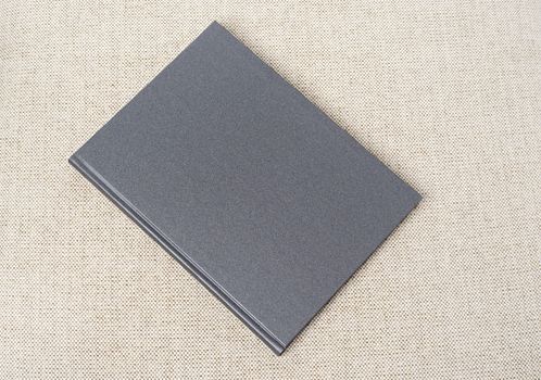 Grey book on the beige fabric material background