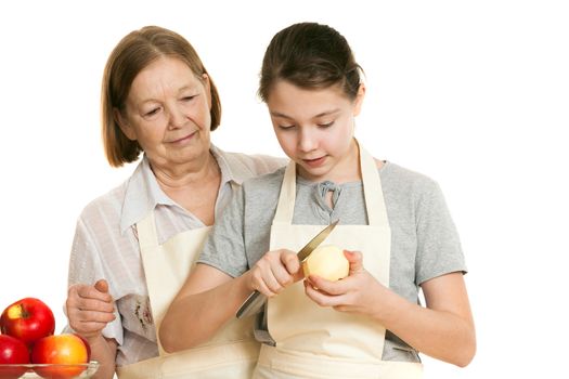 the grandmother teaches the granddaughter to cut off a peel from apple on a white background