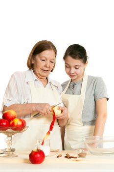 the grandmother teaches the granddaughter to cut off a peel from apple on a white background
