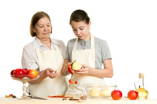 the grandmother teaches the granddaughter to cut off a peel from apple on a white background