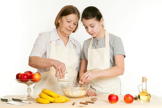 the grandmother and the granddaughter fill ingredients in a bowl on a white background