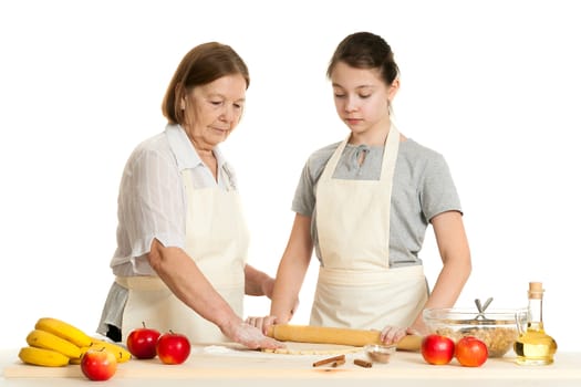 the grandmother and the granddaughter roll dough with a rolling pin for pie on a white background