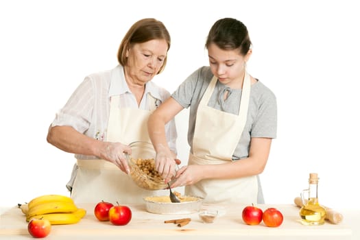 the grandmother and the granddaughter stack a stuffing in a form for pie