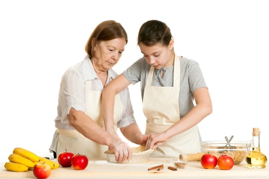 the grandmother and the granddaughter stack dough in a form for pie