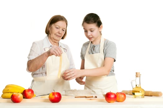 the grandmother and the granddaughter stack dough strips for ornament in a form for pie