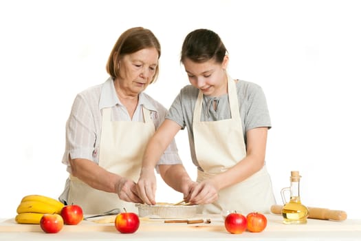 the grandmother and the granddaughter stack dough strips for ornament in a form for pie