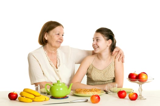 the grandmother and the granddaughter sit at a table with the made pie