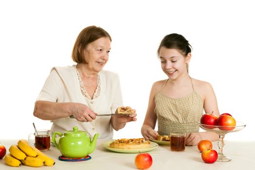 the grandmother treats the granddaughter with pie at a table