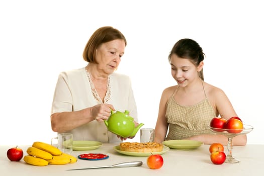 the grandmother treats the granddaughter with tea and pie at a table