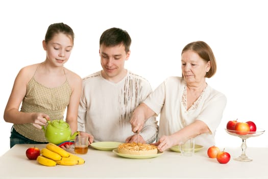 the grandmother and the granddaughter treat the father with pie and tea at a table