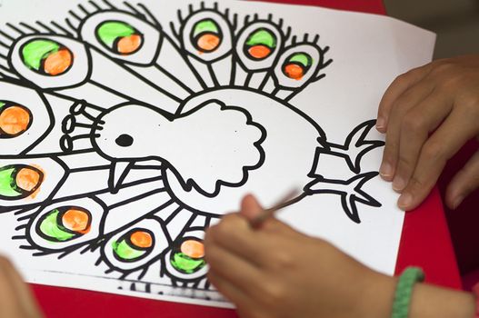 Child painting after a peacock contour drawing
