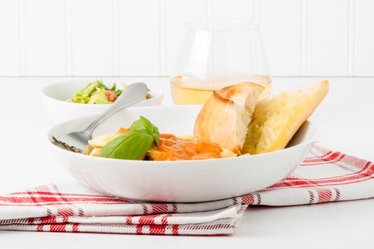 Bowl of tortelloni served with a caesar salad and white wine.  Useful for use on menus and other food service promotions.