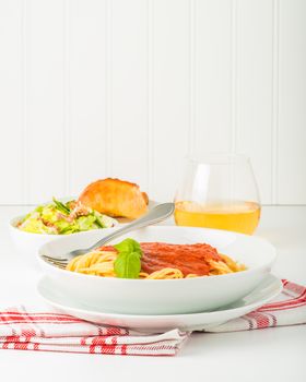 Spaghetti dinner with caesar salad and wine.  Suitable for restaurant menus and other food service promotional materials.