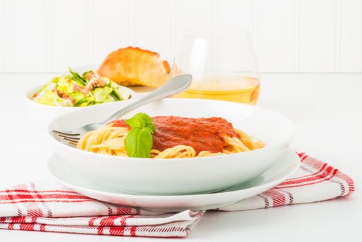 Spaghetti dinner with caesar salad and wine.  Suitable for a restaurant menu or other food service promotions.