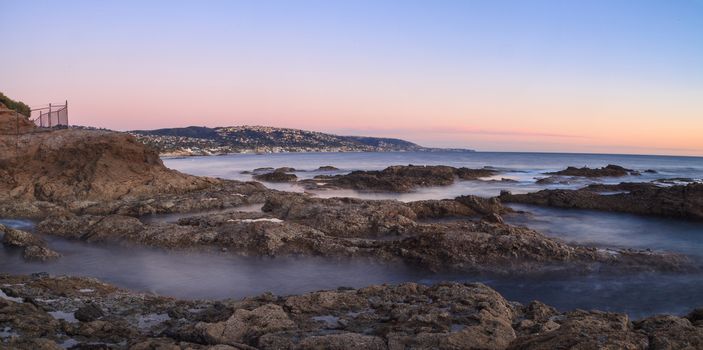 Long exposure of sunset over rocks, giving a mist like effect over ocean in Laguna Beach, California, United States