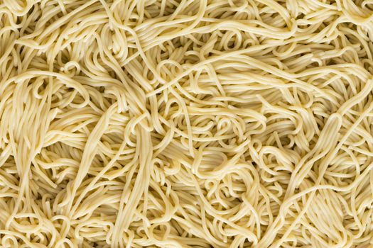 Italian spaghetti pasta background texture with a jumbled pattern of cooked plain noodles viewed full frame close up from overhead