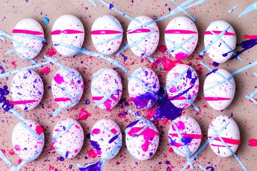 Colorful kids Easter eggs splattered in magenta pink and blue paint arranged in three neat rows over a beige background to celebrate the holiday season in traditional style