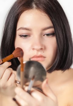 the girl does make-up on a light background