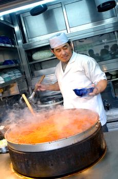 Tokyo, Japan - November 13, 2015: Tsukiji market is  a major tourist attraction, small restaurants surrounding it do brisk business. Tsukiji restaurant chef mix and serve out of that deep  bubbling oozy broth concoction that has been bubbling, intensifying flavors for quite a while.