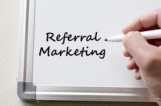 Human hand writing referral marketing on whiteboard