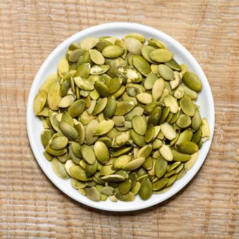 Bowl of cleaned pumpkin seeds, stands on the old boards.