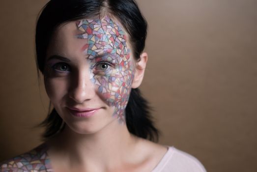 Portrait of a beautiful young girl with creative makeup mask pattern of bright colors.