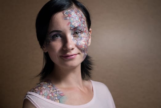 Portrait of a beautiful young girl with creative makeup mask pattern of bright colors.