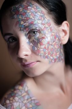 Portrait of a beautiful young girl with creative makeup mask pattern of bright colors.