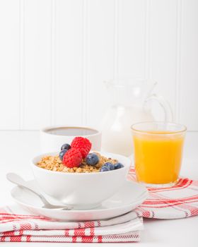Bowl of granola and fresh berries with coffee and orange juice.