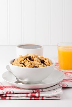 Bowl of granola and raisins with orange juice and coffee