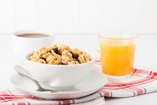 Bowl of granola with raisins served with orange juice and coffee.