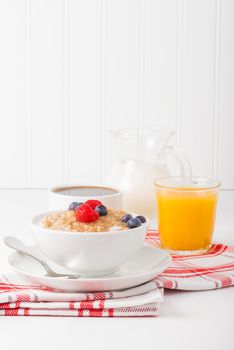 Bowl of oatmeal and fresh berries with coffee and orange juice.