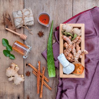 Natural Spa Ingredients herbal compress ball and herbal  Ingredients  for alternative medicine and relaxation Thai Spa theme with silk fabric on old wooden background.