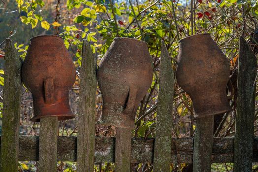 Three clay pitchers on the wooden fence. Clay pitchers.