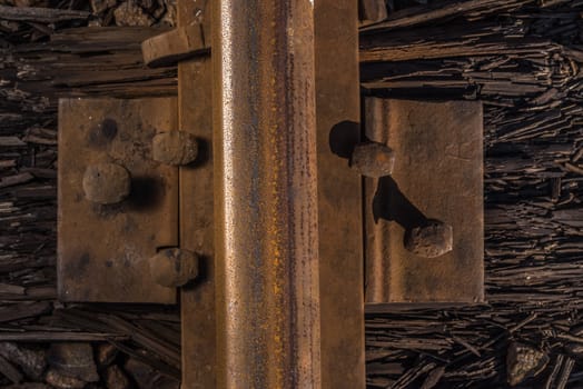 Rusty rails crammed into a rotten sleeper. Old railroad.